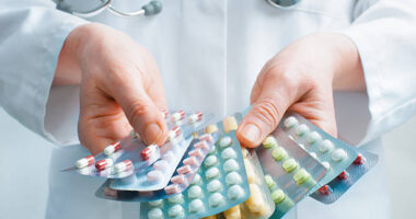 A clinican holds out multiple packets of medication.