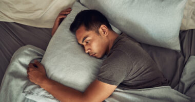 A man lies in bed fully awake.