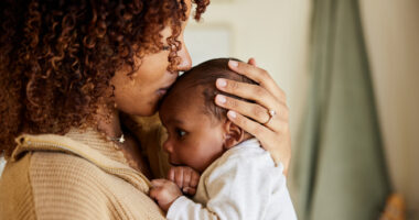 A mother kisses her baby boy on his head.