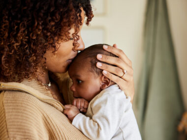 A mother kisses her baby boy on his head.
