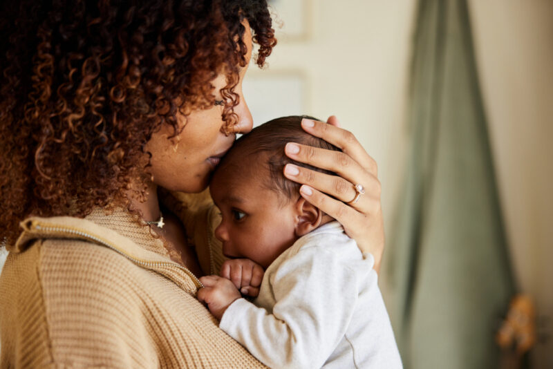 A mother kisses her baby boy on his head.