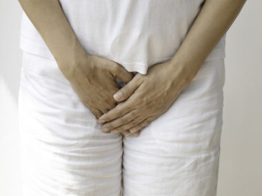 A person is shown standing, with hands placed over the groin area.