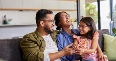 A girl sits on her mother's lap and enjoys a laugh with her parents.