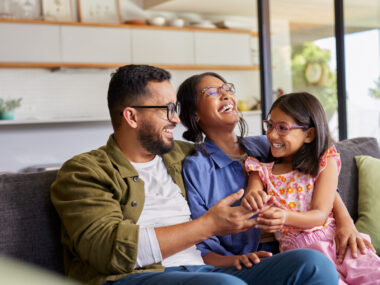 A girl sits on her mother's lap and enjoys a laugh with her parents.