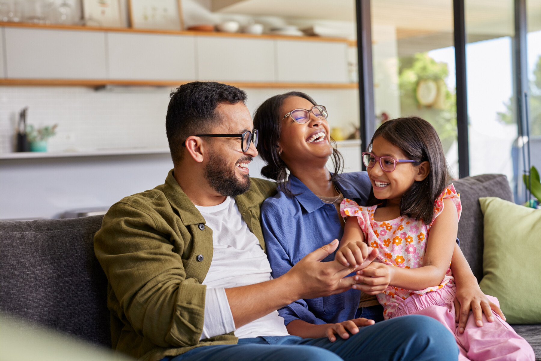 A girl sits on her mother's lap and enjoys a laugh with her parents.