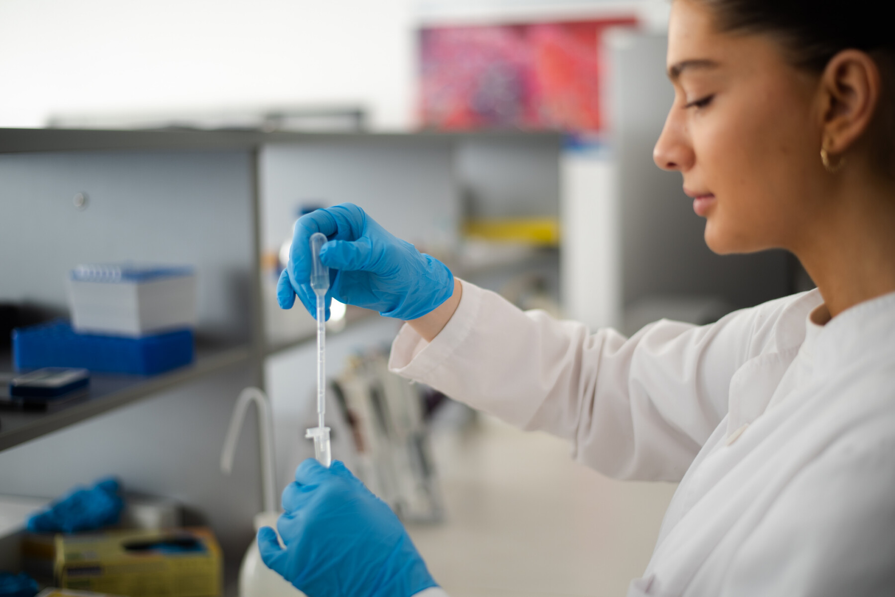 A person in a white coat works in a lab.