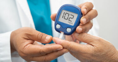 A clinician uses a finger prick device to test a patient's blood sugar levels.