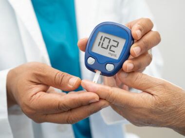 A clinician uses a finger prick device to test a patient's blood sugar levels.
