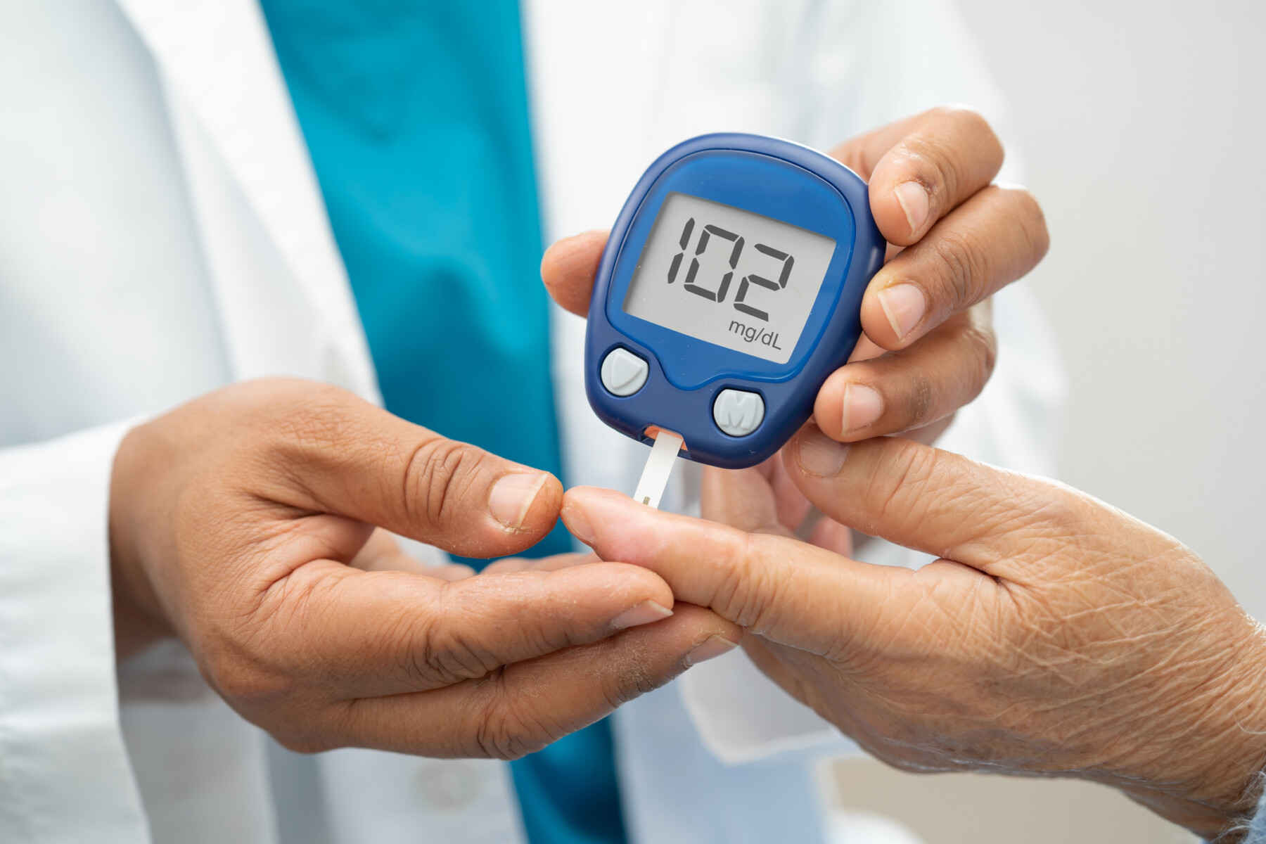 A clinician uses a finger prick device to test a patient's blood sugar levels.