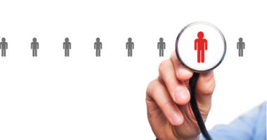 A hand holds up a stethoscope, with the form of a person visible in the chestpiece of the medical device.