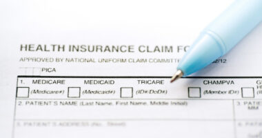 A health insurance claim form document is shown along with a pen.