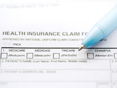 A health insurance claim form document is shown along with a pen.