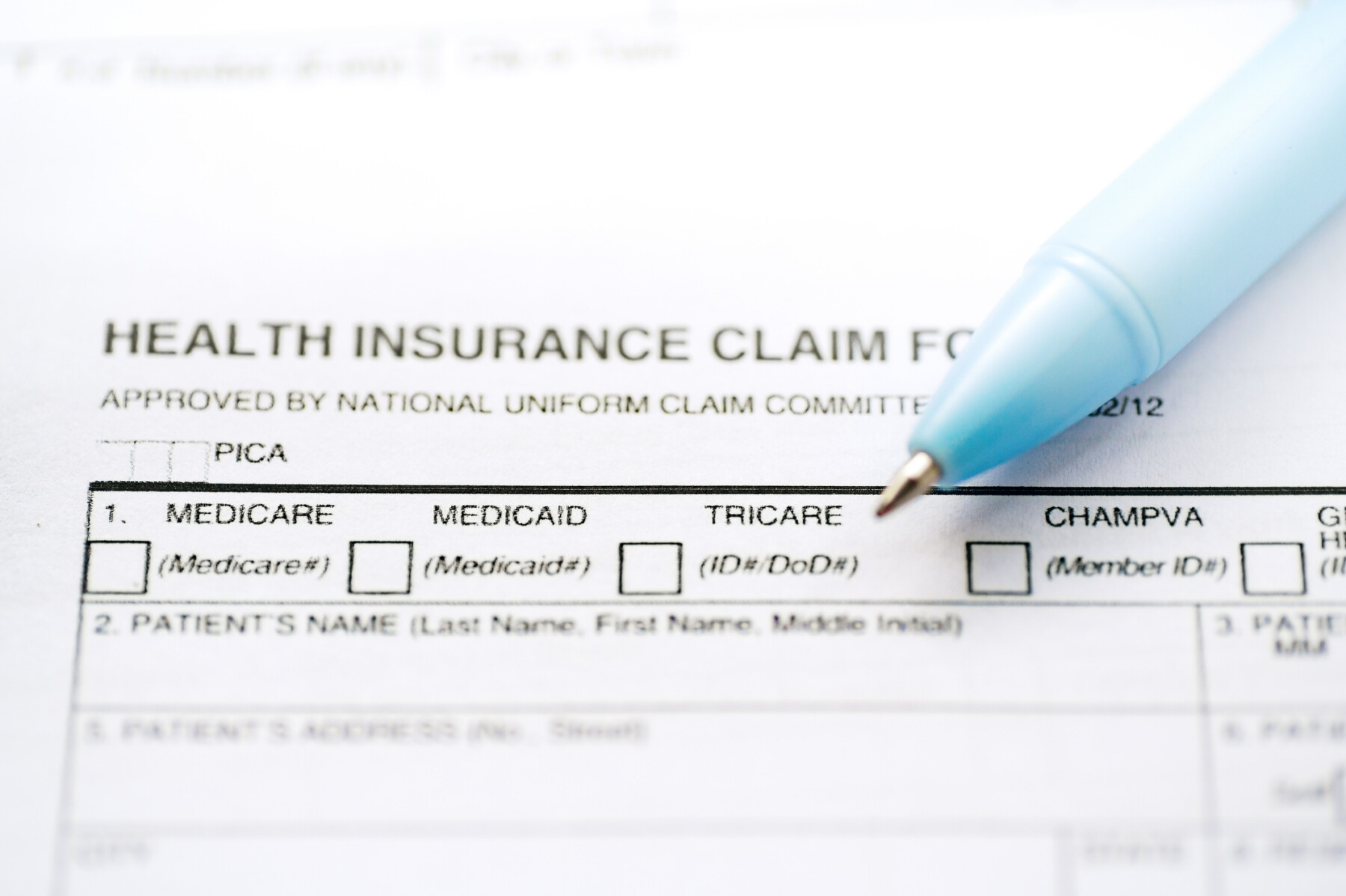 A health insurance claim form document is shown along with a pen.