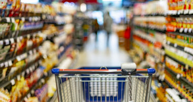 A shopping cart is shown in a grocery store aisle.