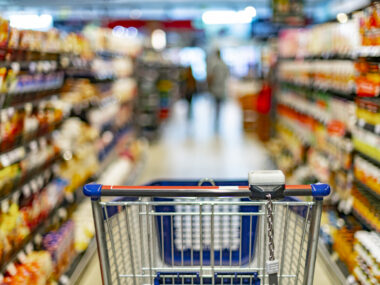 A shopping cart is shown in a grocery store aisle.
