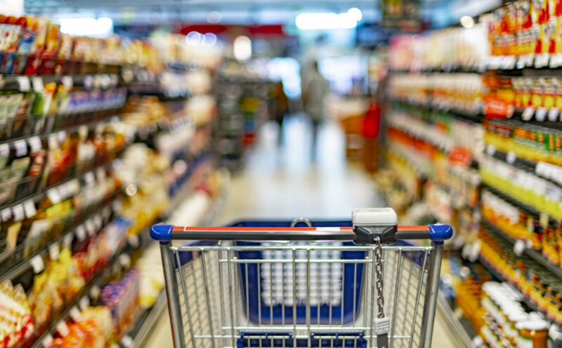 A shopping cart is shown in a grocery store aisle.