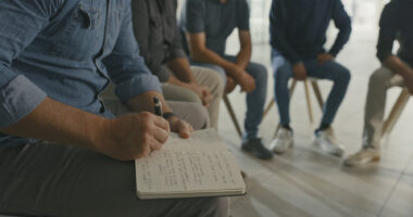 A photo shows a therapist taking notes during a group session.