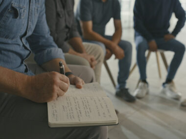 A photo shows a therapist taking notes during a group session.