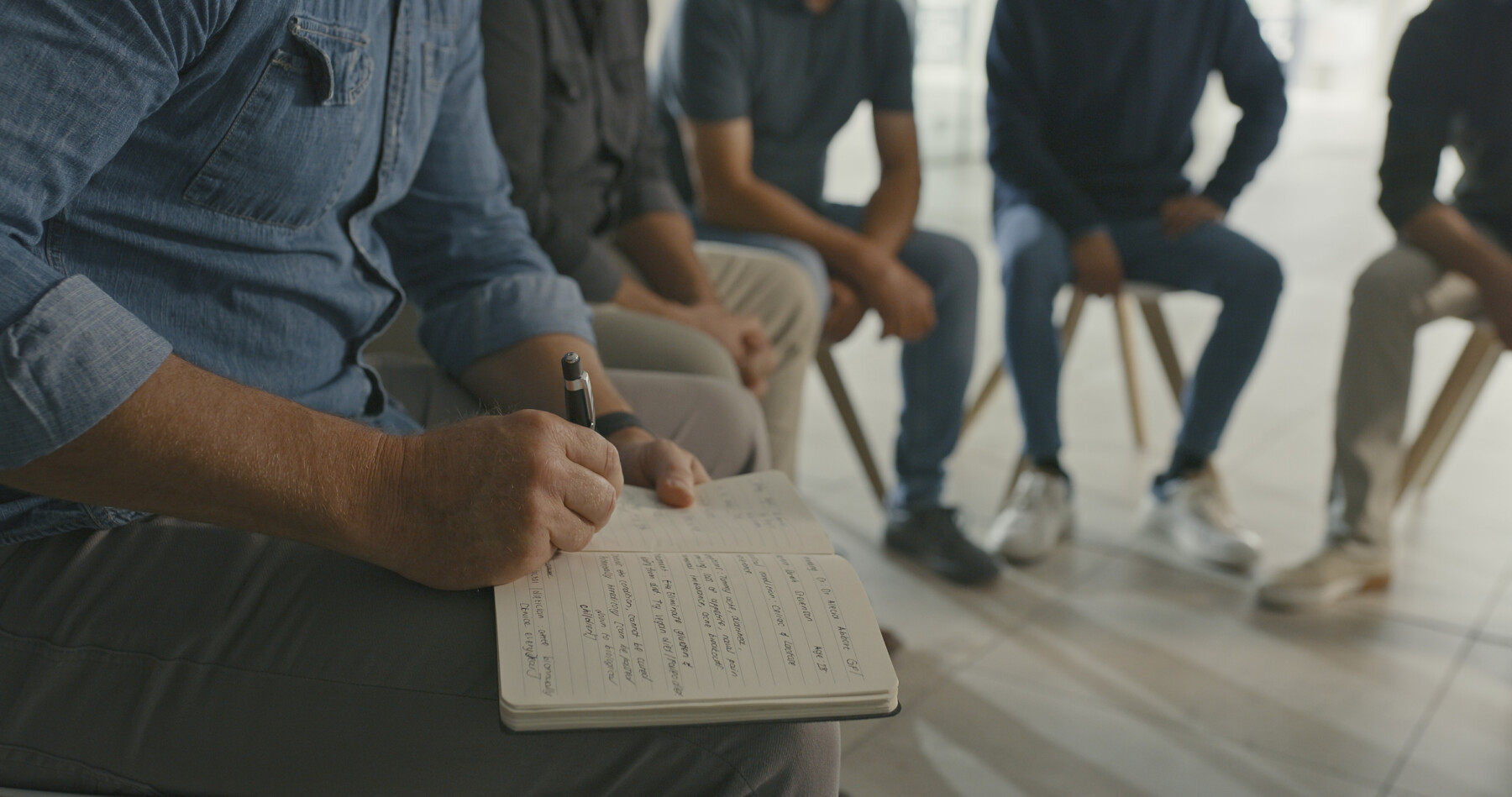 A photo shows a therapist taking notes during a group session.