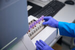 The hands of a laboratory technician are seen while performing a general blood test. The biomaterial is in special tubes.