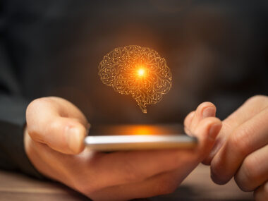 An AI image of the human brain is seen above a smartphone held in a person's hand.