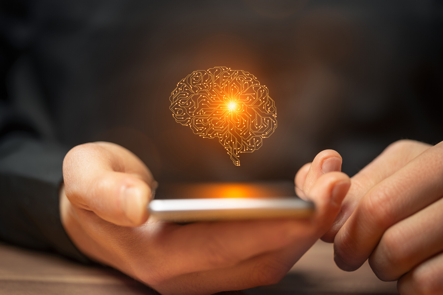 An AI image of the human brain is seen above a smartphone held in a person's hand.