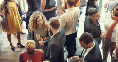 A photograph shows people mingling at a reception.