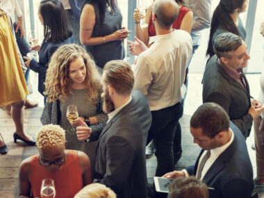 A photograph shows people mingling at a reception.