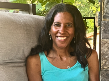 A smiling woman is pictured from the shoulders up.