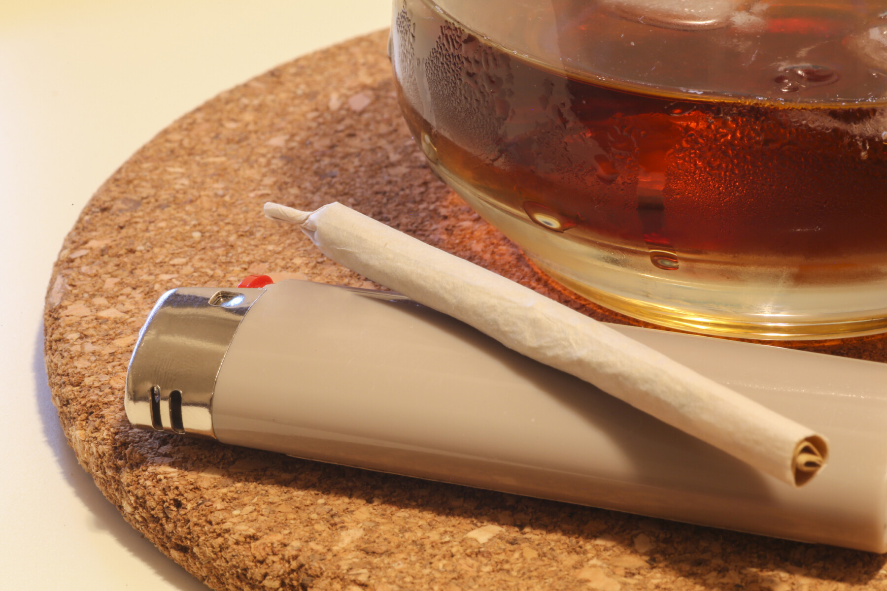 A photo shows a marijuana cigarette and a glass of amber liquid.
