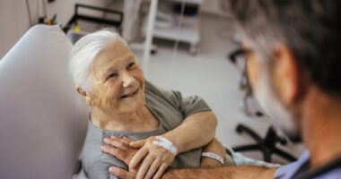 An image of an older woman talking with a healthcare professional during a medical visit.