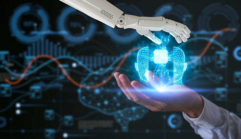 A robot hand and a human hand hold a virtual AI icon.
