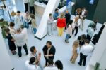 A large group of people are seen networking at a conference.