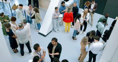 A large group of people are seen networking at a conference.