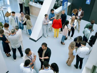 A large group of people are seen networking at a conference.