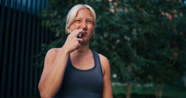 A woman uses a nasal spray.