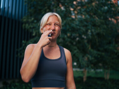 A woman uses a nasal spray.