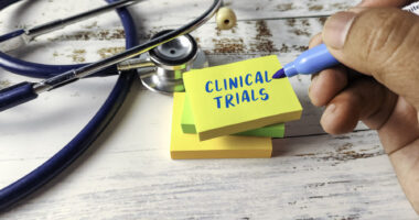 A hand holding a blue marker is seen next to a stethoscope and a stack of small Sticky Note pads, with the words 
