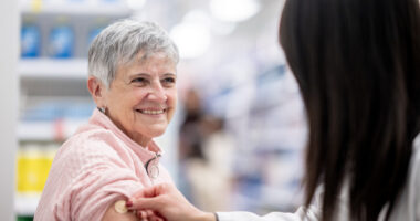 A woman receives a vaccine in a pharmacy.