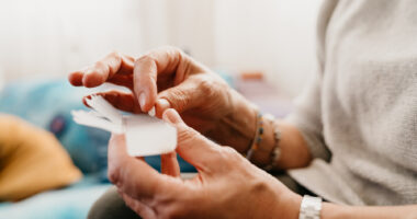 A person is shown holding her pill organizer.