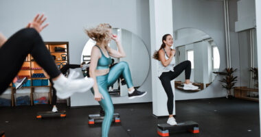 Women are doing high knees in an exercise class.