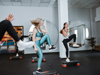 Women are doing high knees in an exercise class.