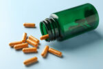 An image of capsules and an overturned bottle on a light blue background.