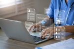 A doctor is seen using a laptop to manage electronic medical records.