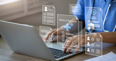 A doctor is seen using a laptop to manage electronic medical records.