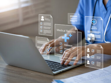 A doctor is seen using a laptop to manage electronic medical records.