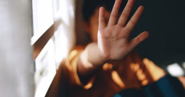 A young person holds up their hand is a stop gesture.