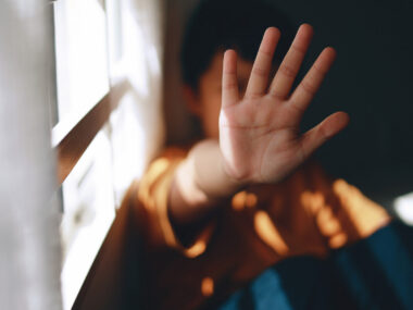 A young person holds up their hand is a stop gesture.