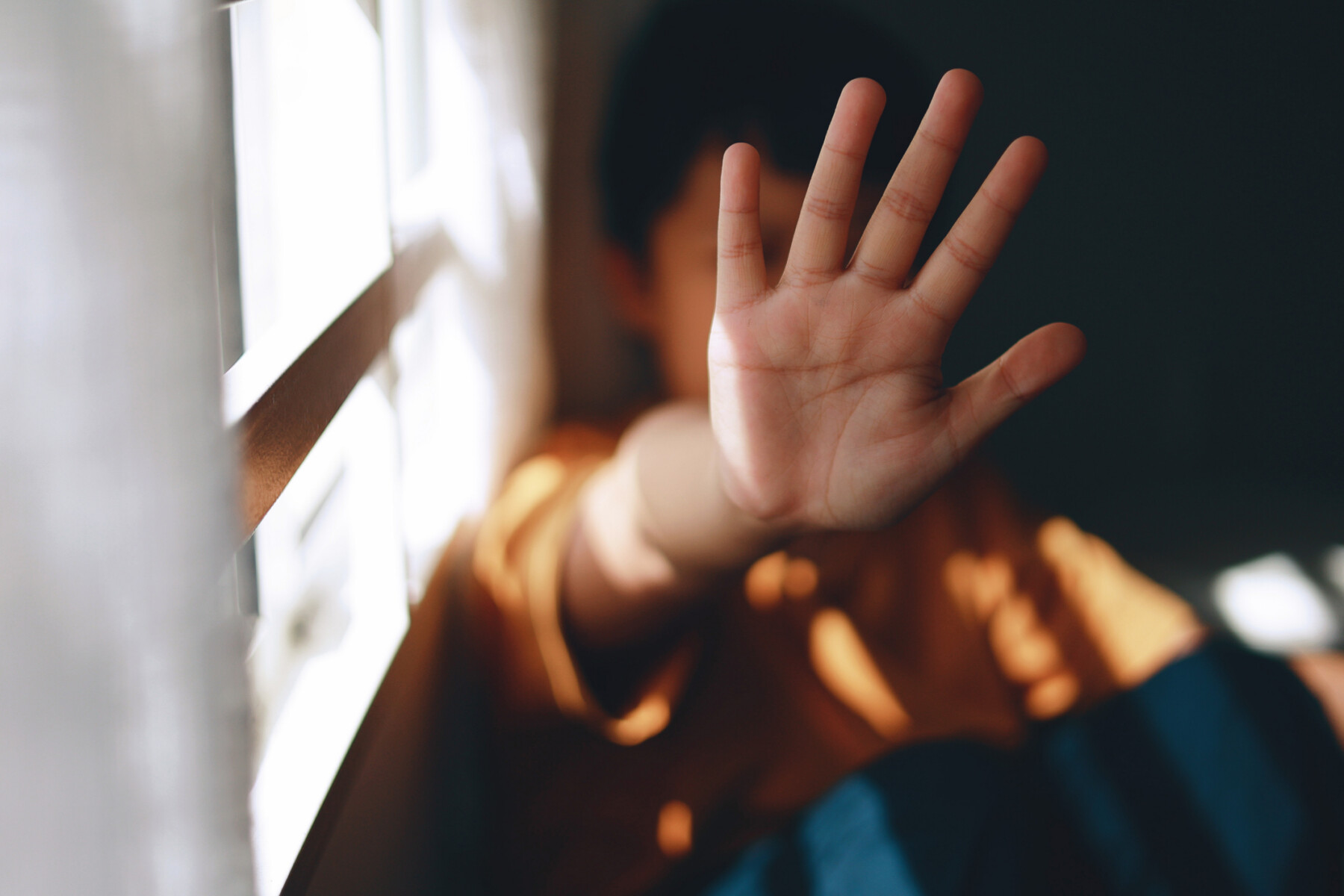 A young person holds up their hand is a stop gesture.