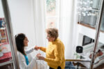 A photo shows a nurse supporting a woman while she practices walking.